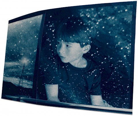 young boy looking outside of car window while it is raining