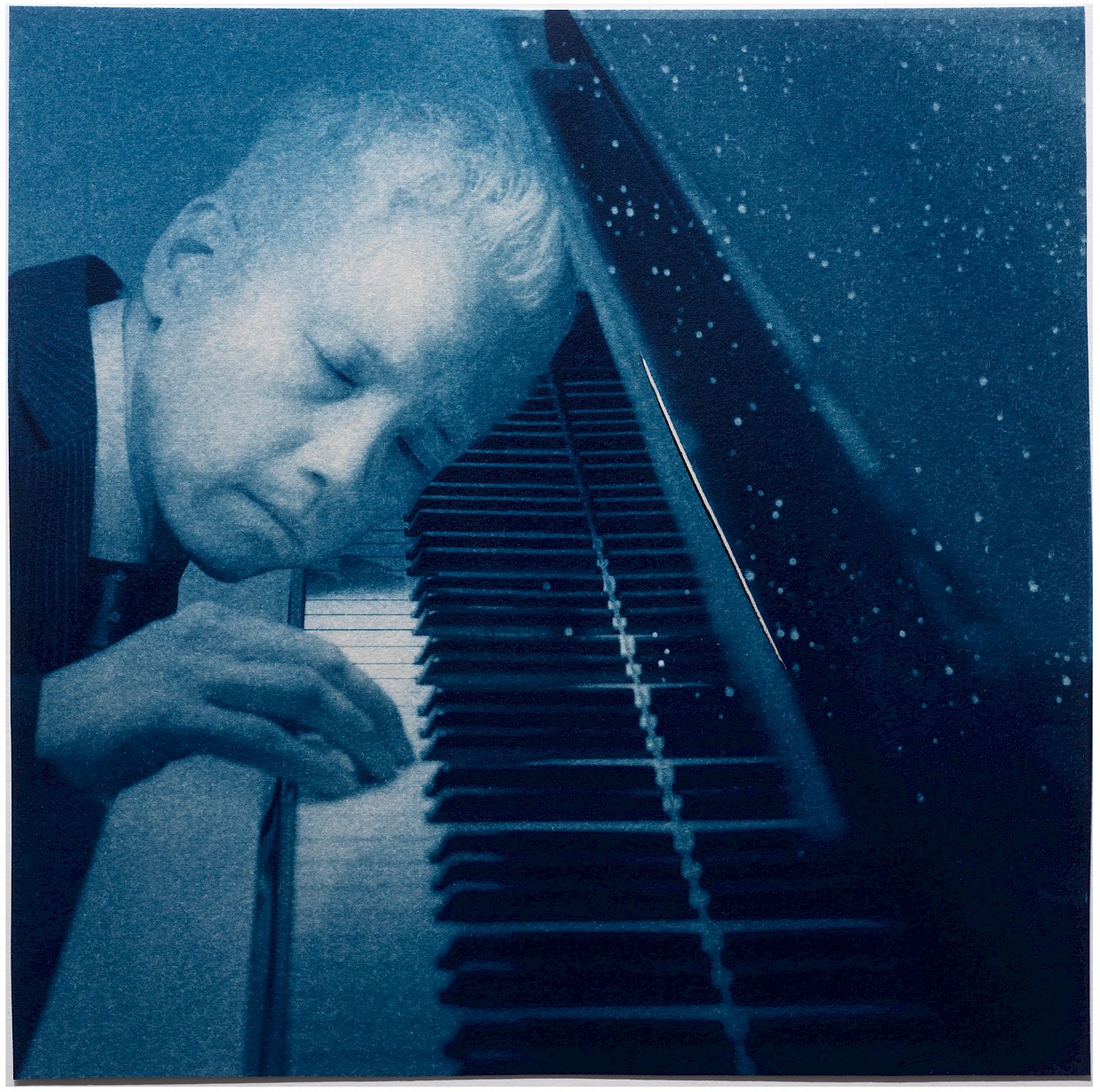 man with head on piano keys listening intently with stars coming from piano