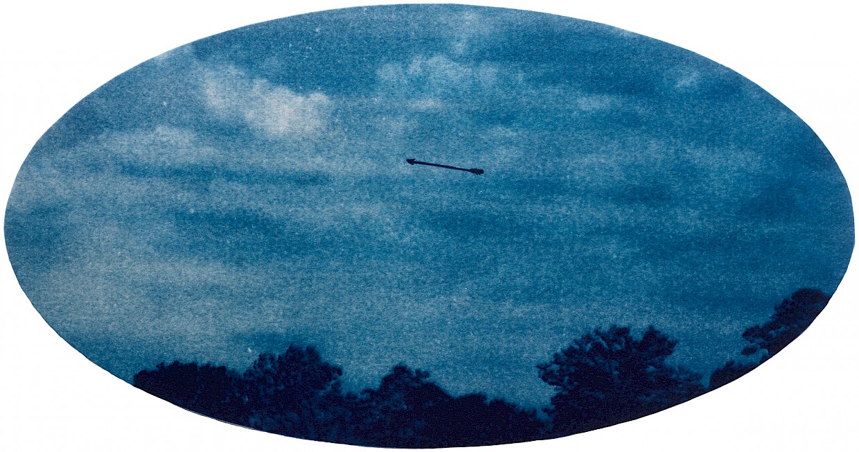 cyanotype image arrow against sky with trees in bottom